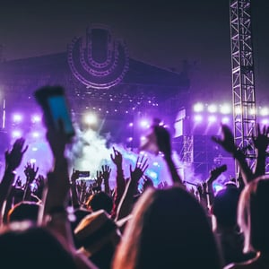 Yleisö purppuranvärisesti valaistulla musiikkifestivaalin lavalla