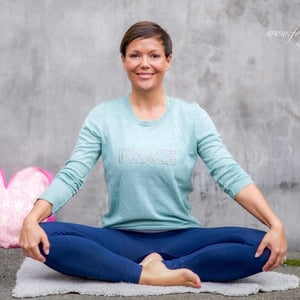 Portrett av Trine Berge fra Bodø Yogafestival sittende i lys genser.