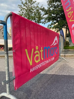 Festivalområde med fargerik Våt Moro Festival-banner og trær i bakgrunnen.